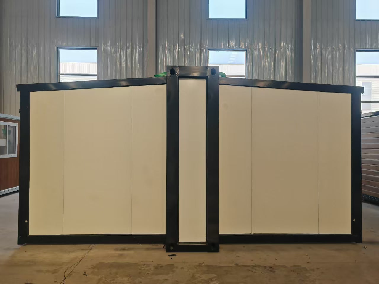 Two large beige panels with black frames in a room with metallic walls and windows.