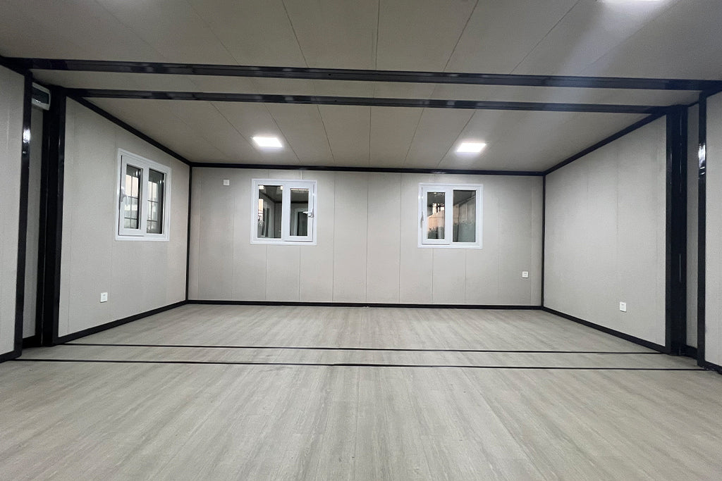 Empty room with gray walls, wooden floor, and three windows.