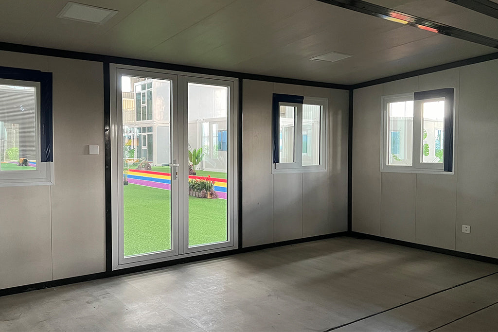 Modern room with large glass door showing green grass and colorful flags outside