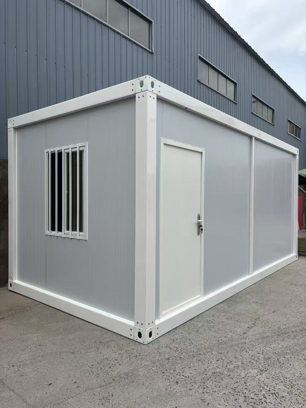 Modular building container with a door and window on a concrete surface.
