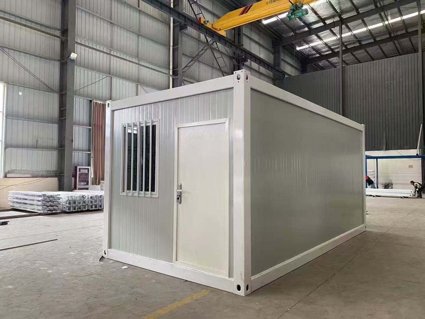 Modular building container in a warehouse setting with a crane in the background.