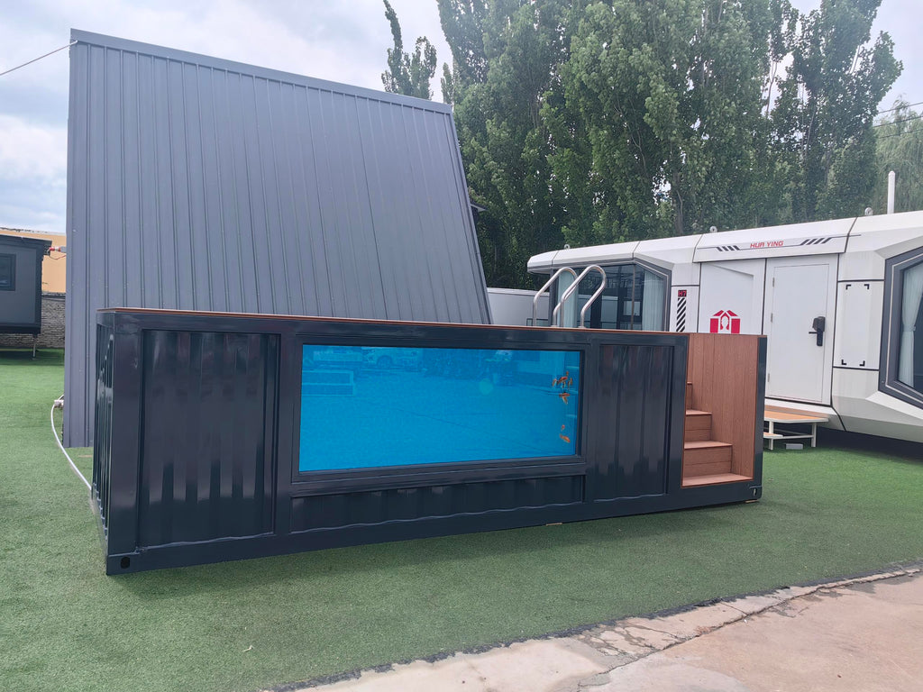 Modular building made from shipping containers with a blue screen on a grassy area.