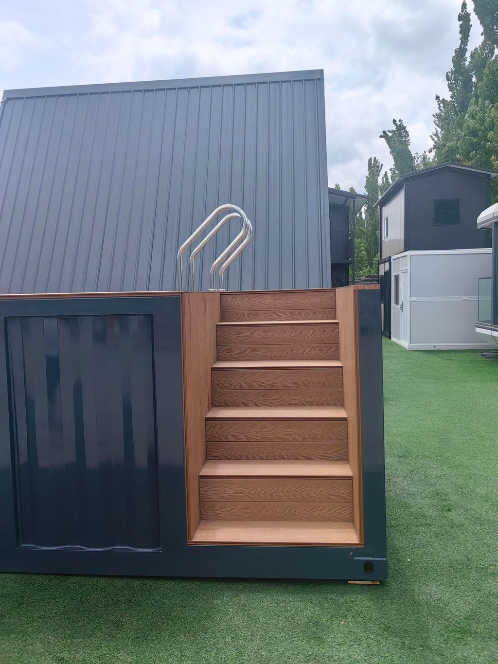 Small building with wooden steps leading up to a door on a grassy area
