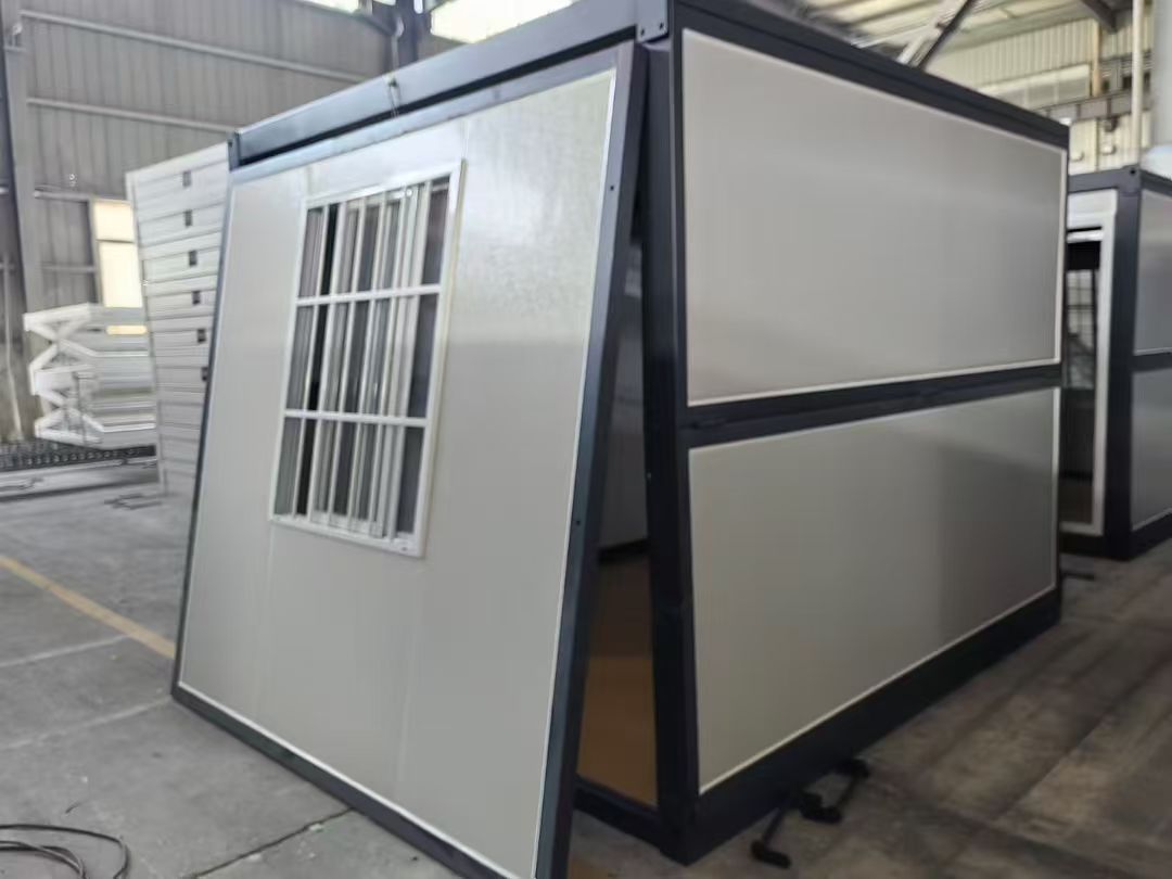 Metallic container or pod with a window on a concrete floor, possibly in an industrial setting.