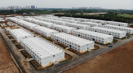 Large-scale temporary housing construction site with multiple white modular buildings.