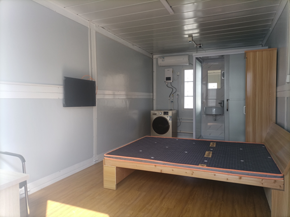 Small room with a bed, television, and bathroom in the background