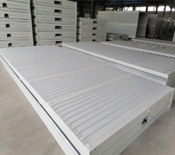 Stacks of white metal panels on a concrete floor with a warehouse setting.